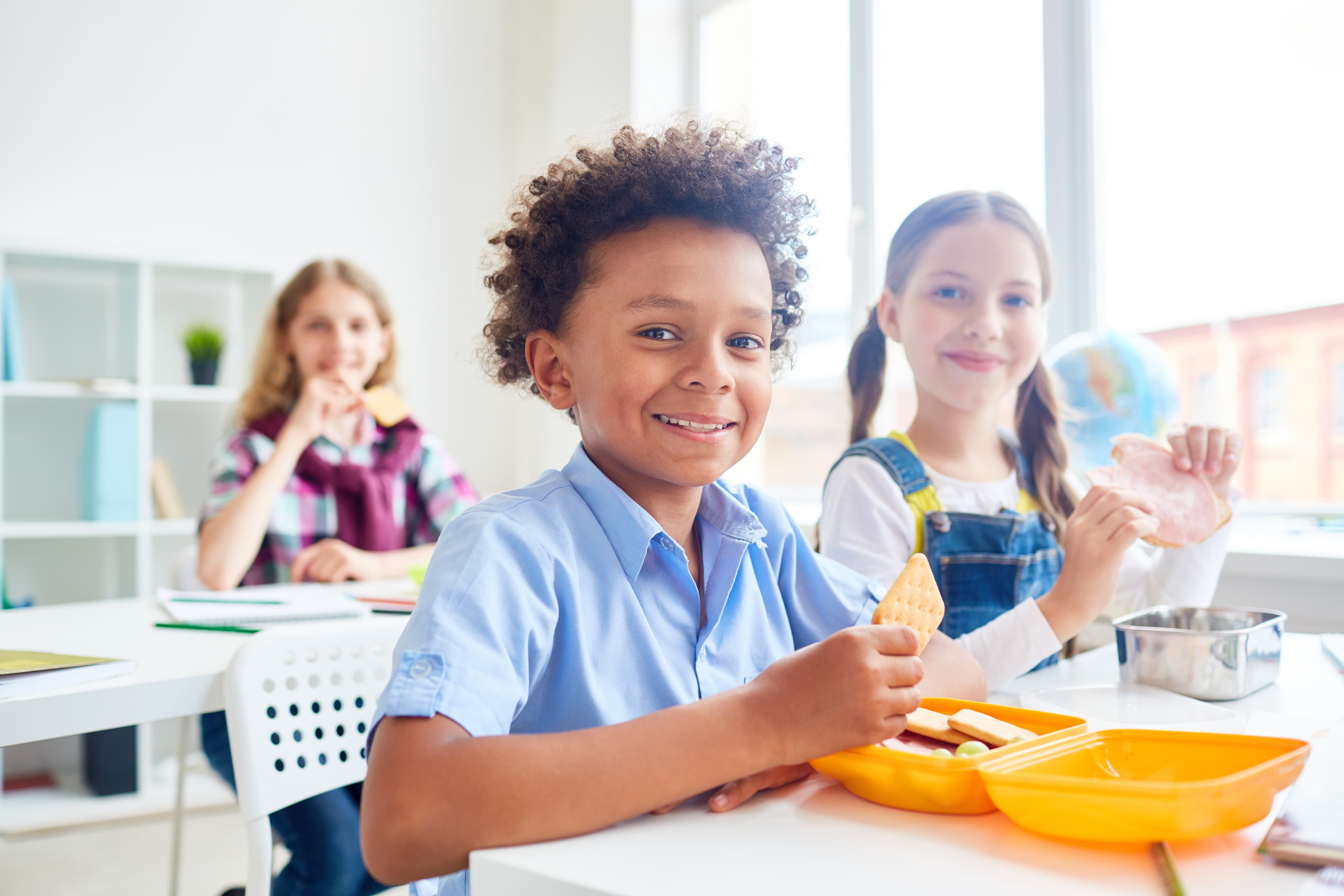 Des élèves souriants prennent leur collation en classe